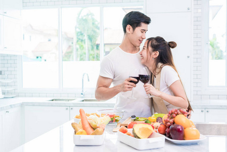 亚洲情侣或情侣在家里的厨房里喝葡萄酒。爱与幸福概念甜蜜的蜜月和情人节主题