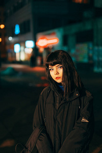 年轻的日本女孩站在霓虹灯附近, 摆出照相机的姿势