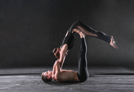 年轻的体育夫妇练习 acroyoga。双平衡