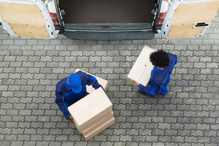 送货人员从卡车上卸下纸板箱的高角度视图