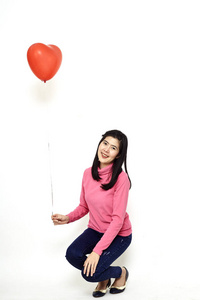 亚洲年轻女子，留着长长的黑发，穿着粉红色的长衫，牛仔裤，白色背景下还有红心气球