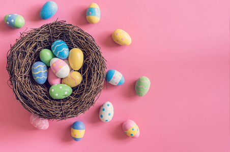 五颜六色的复活节彩蛋在巢在粉红色柔和的颜色背景机智