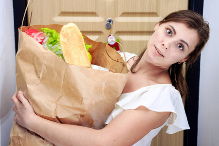 拿着蔬菜购物袋的年轻妇女。妇女家庭主妇手中的食品纸包装