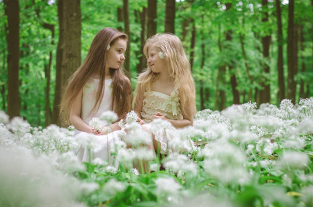 两个美丽的女孩坐在草地上