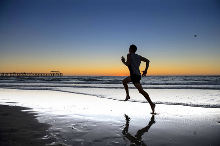 剪影年轻动态运动员赛跑者与适合强的身体训练在夏天日落海滩赤脚奔跑在体育健康生活方式概念