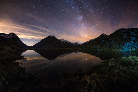 银河星空倒映在阿尔卑斯高山上的湖面上。鱼眼景观失真与180度景观