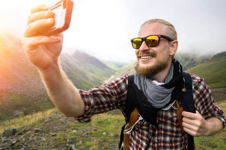 留着胡子的男人在山景的背景下自拍。 旅行徒步旅行概念