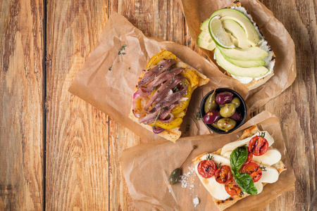 把美味的三明治放在木桌上的羊皮纸上