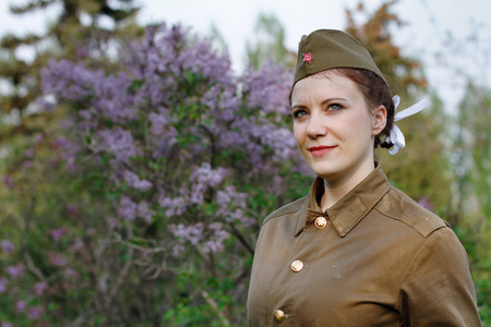 以紫丁香为背景的第二次世界大战形式的漂亮苏联女兵