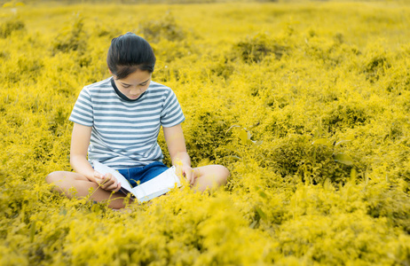 年轻女孩读一本书在金子草甸乡村 natur