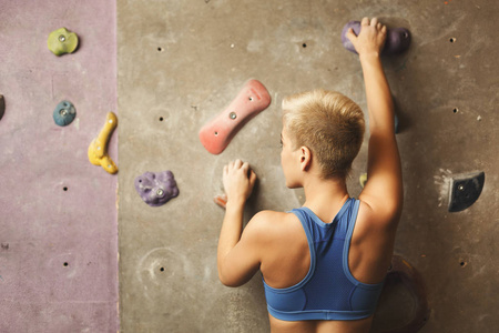 体操的年轻妇女攀登人造石墙壁
