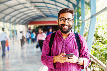 大胡子的印度男子在地铁站使用他的智能手机应用程序