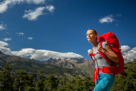 漂亮的女徒步旅行者在高山上背着巨大的背包