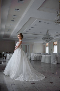 美丽的新娘穿着婚纱，在一个豪华的白色房间里，有一个大吊灯。