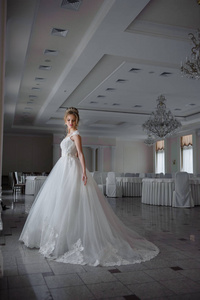 美丽的新娘穿着婚纱，在一个豪华的白色房间里，有一个大吊灯。