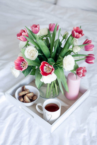浪漫的早餐在床上。花的花束。玫瑰和郁金香。春天.情人节国际妇女节。舒适