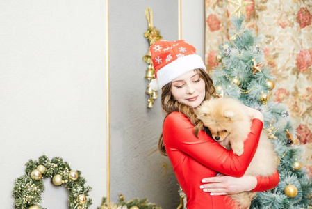 女孩在红色礼服与狗在圣诞树附近