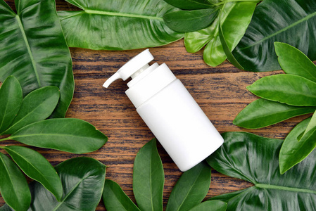 天然护肤美容产品概念, 化妆品瓶容器上的绿色草药叶子背景, 空白标签的品牌模拟