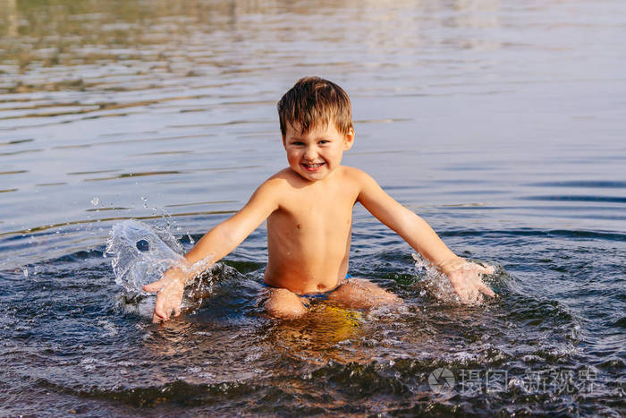 小男孩溅水阳光明媚的夏日在温暖的湖水中游泳