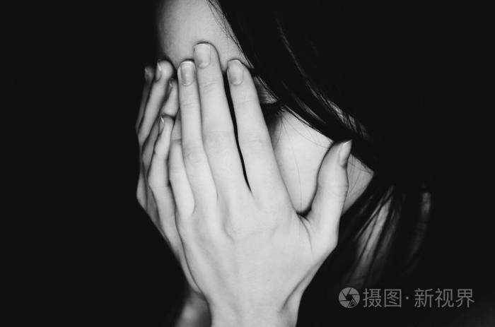 哭泣的年轻女孩用手遮住她的脸黑白色照片-正版商用