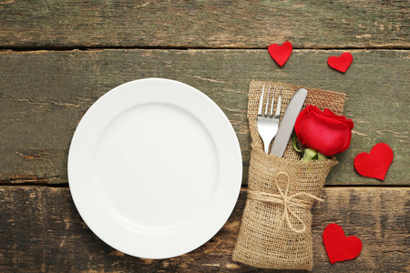 木制桌子上有红色玫瑰和白色盘子的厨房餐具