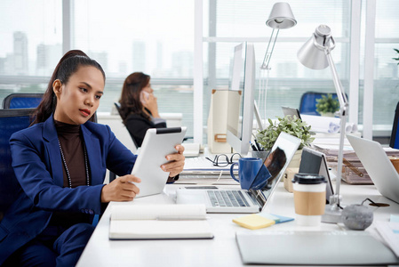 菲律宾商界女性在办公室工作时阅读平板电脑上的信息