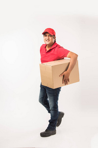 送货概念肖像快乐印度或送货员穿红色或绿色制服步行或跳跃，检查或呈现纸板箱与复制空间。