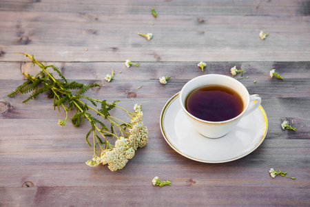 一杯茶在一张木桌上, 用白色的花朵