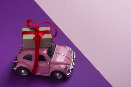 粉红色复古玩具车送礼品盒在柔和的背景。顶部视图