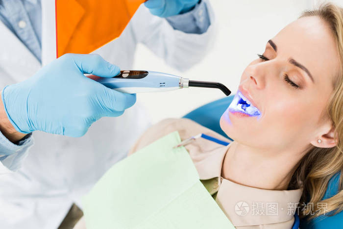 牙科医生在现代牙科诊所使用紫外线灯治疗病人牙齿