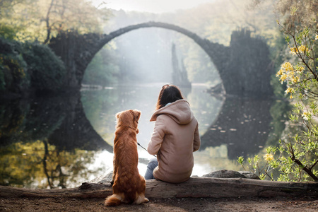 带着狗在桥上的女孩。新斯科舍省的鸭子在公园的桥上鸣叫猎犬