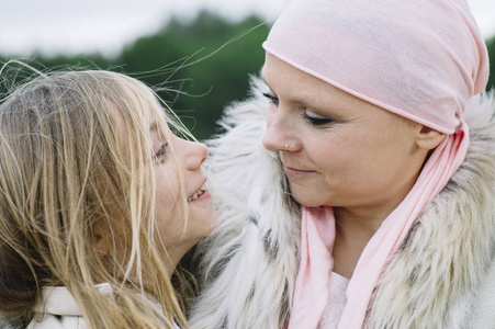 一个患癌症的妇女挨着她的女儿。一个女孩在拥抱