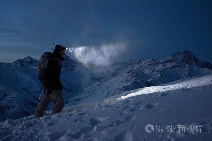 勇敢的夜探员爬上高高的雪山,用前照灯照亮道路 极端探险 滑雪之旅.