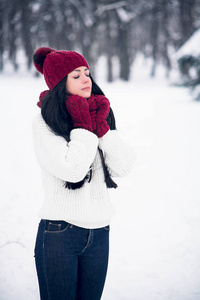 一个甜美, 温柔和感性的年轻女子穿着白色毛衣和明亮的帽子, 围巾和手套