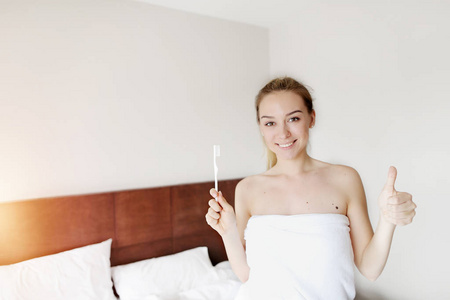 毛巾上的年轻女子的肖像拇指用牙刷清洁牙齿