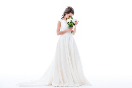 优雅的新娘身着传统服装，嗅着婚礼花束，孤立在白色上