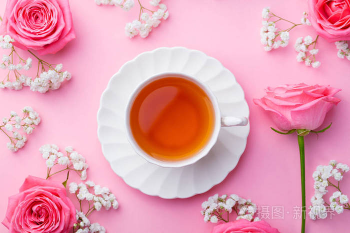 在粉红色的背景上有鲜花的杯茶.顶部视图.复制空间