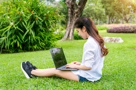 年轻女子在公园中使用的笔记本电脑