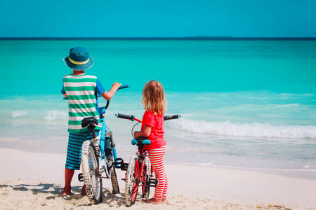 小男孩和女孩在海滩骑自行车