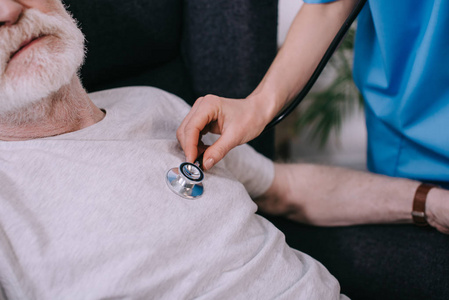 老年男性听诊器检查心跳的女性护士近距离观察
