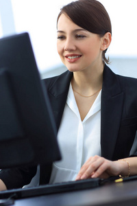 在计算机上工作信心十足的年轻商业女人的特写