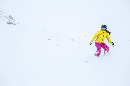 从山坡上开发发滑雪板的女运动员戴头盔的形象