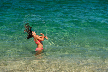 女孩有乐趣沐浴在海和飞溅的水