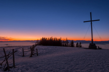 美丽的日落在山顶十字架雪盖的山 Schoeckl