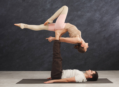 年轻夫妇在垫子上练习 acroyoga