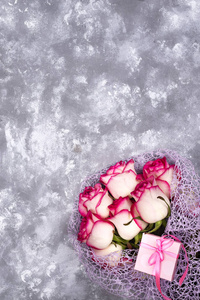 红白玫瑰花花束与粉红色礼品盒在石桌上