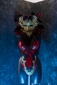 化妆舞会威尼斯红色面具和红色紧身胸衣与黄金和黑色花边织物在金属胸牌。 派对或服装会议的手工馅饼