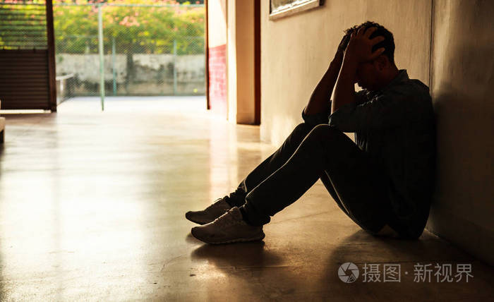 情绪时刻:男人坐着,双手抱着头,强调悲伤的年轻男性