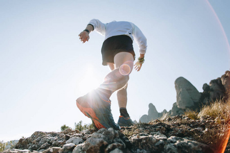 强壮的小腿，肌肉超马拉松运动员和运动员在比赛或马拉松上的山路，专业跑鞋鞋底运动鞋和岩石地形表面