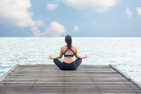 健康的女性生活方式冥想平衡瑜伽练习和能量在早上的桥上海滨。 健康概念